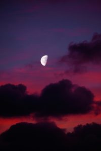 Half moon shining in a colorful twilight sky.