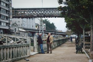 Two men conversing by a riverside pathway.