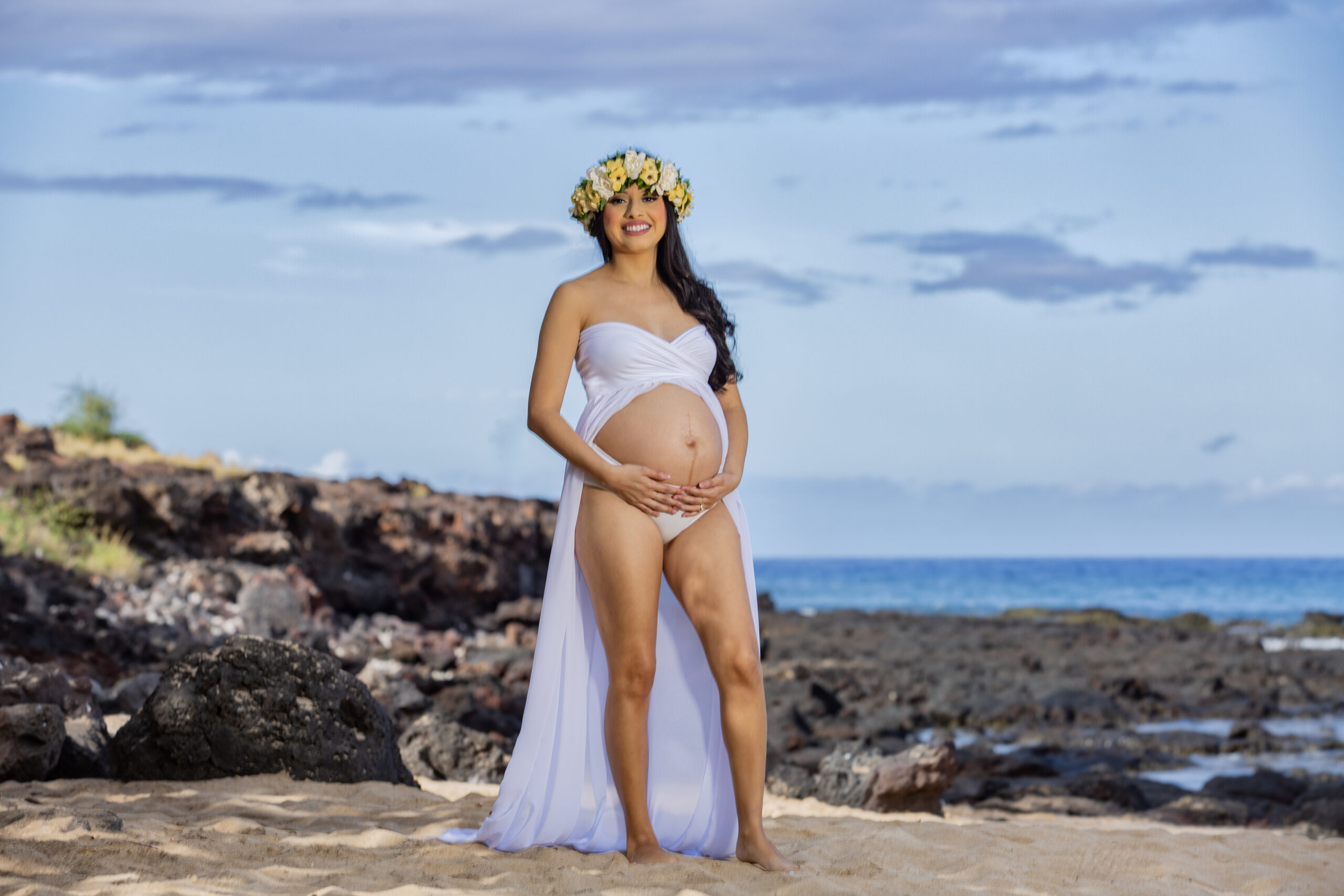 Pregnant woman in a floral crown at the beach.