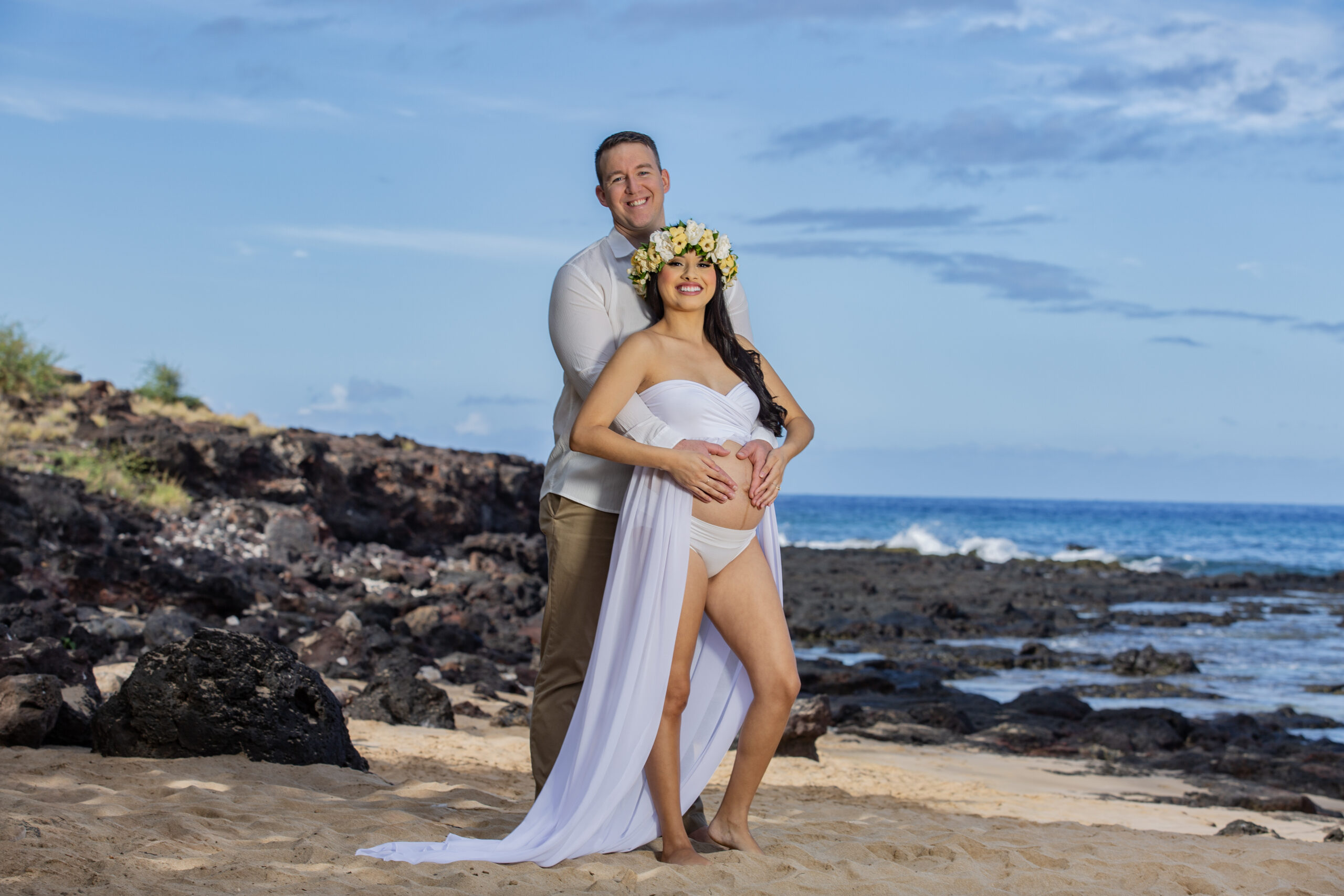 Couple celebrating pregnancy on a beach.