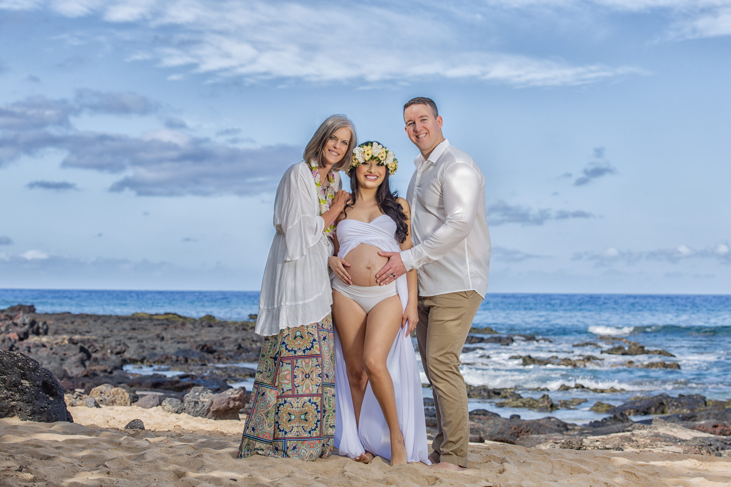 Pregnant woman with family on beach at sunset.