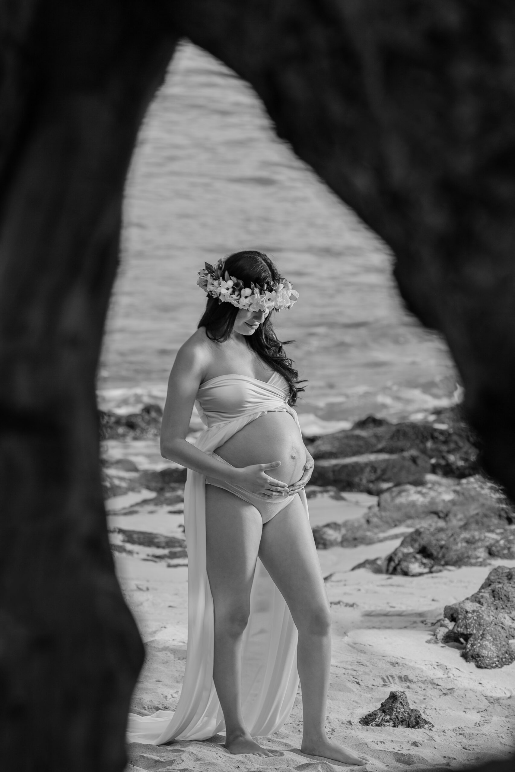 Pregnant woman in beach setting, wearing floral crown.