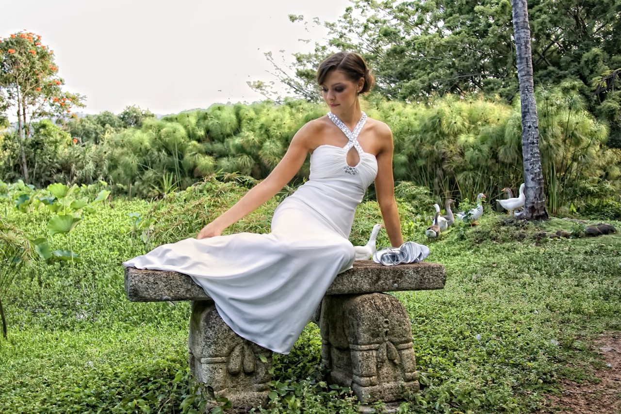 Woman in a white dress sitting on stone bench.