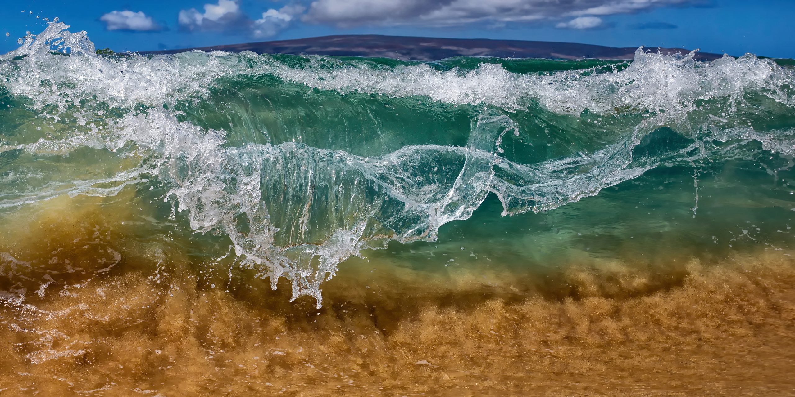 Close-up of crashing ocean waves on sandy beach.