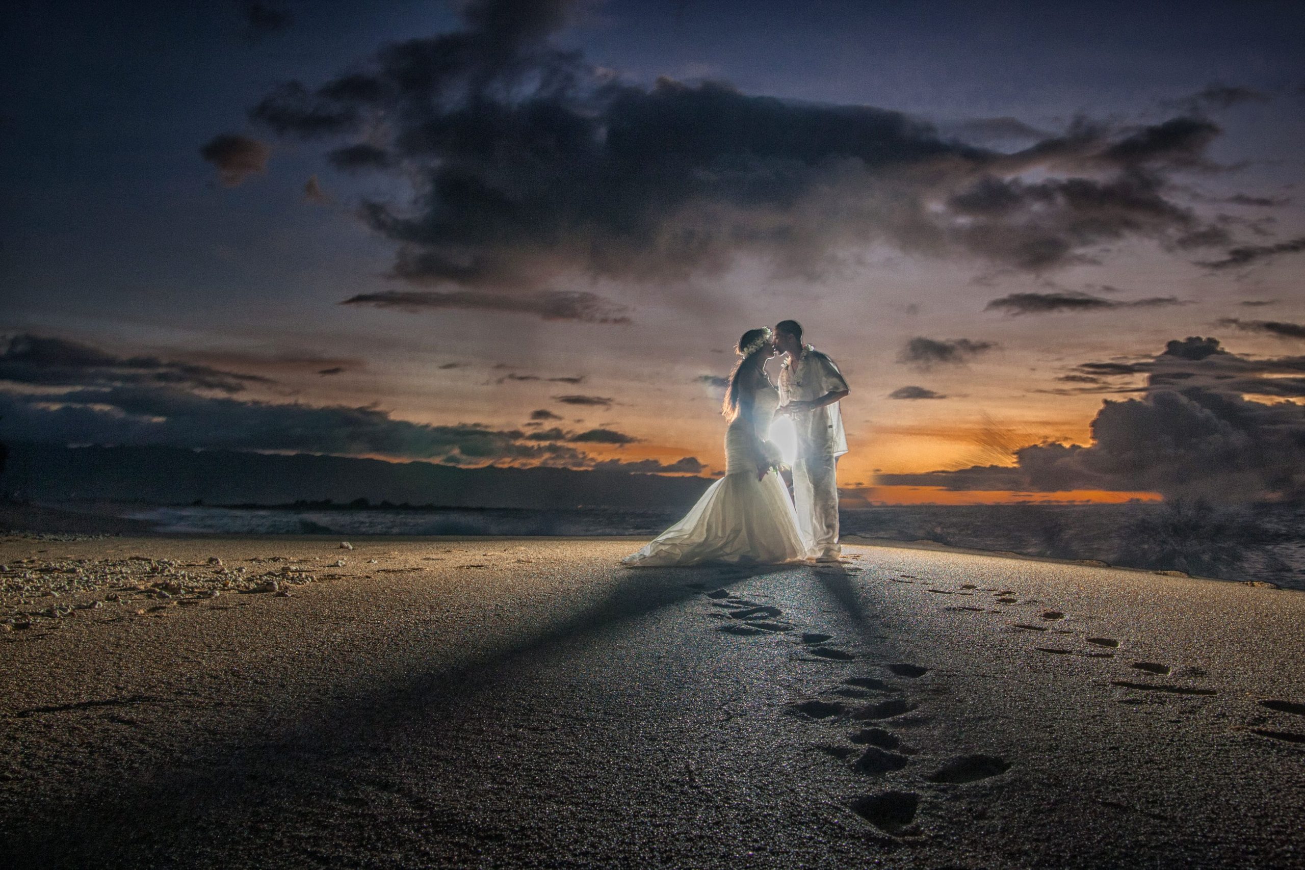 Couple kissing at sunset on a beach.