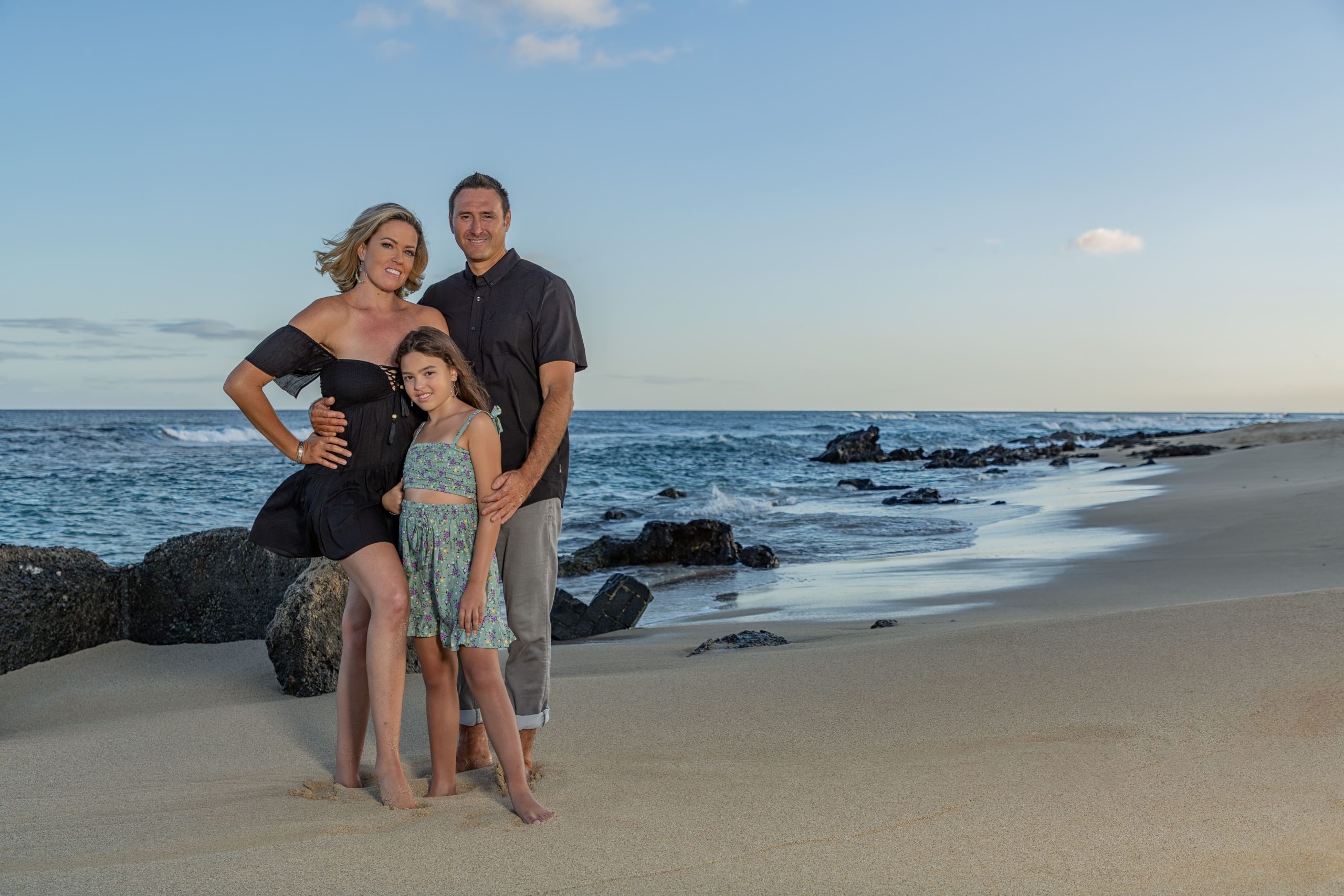 Family posing together on the beach at sunset.